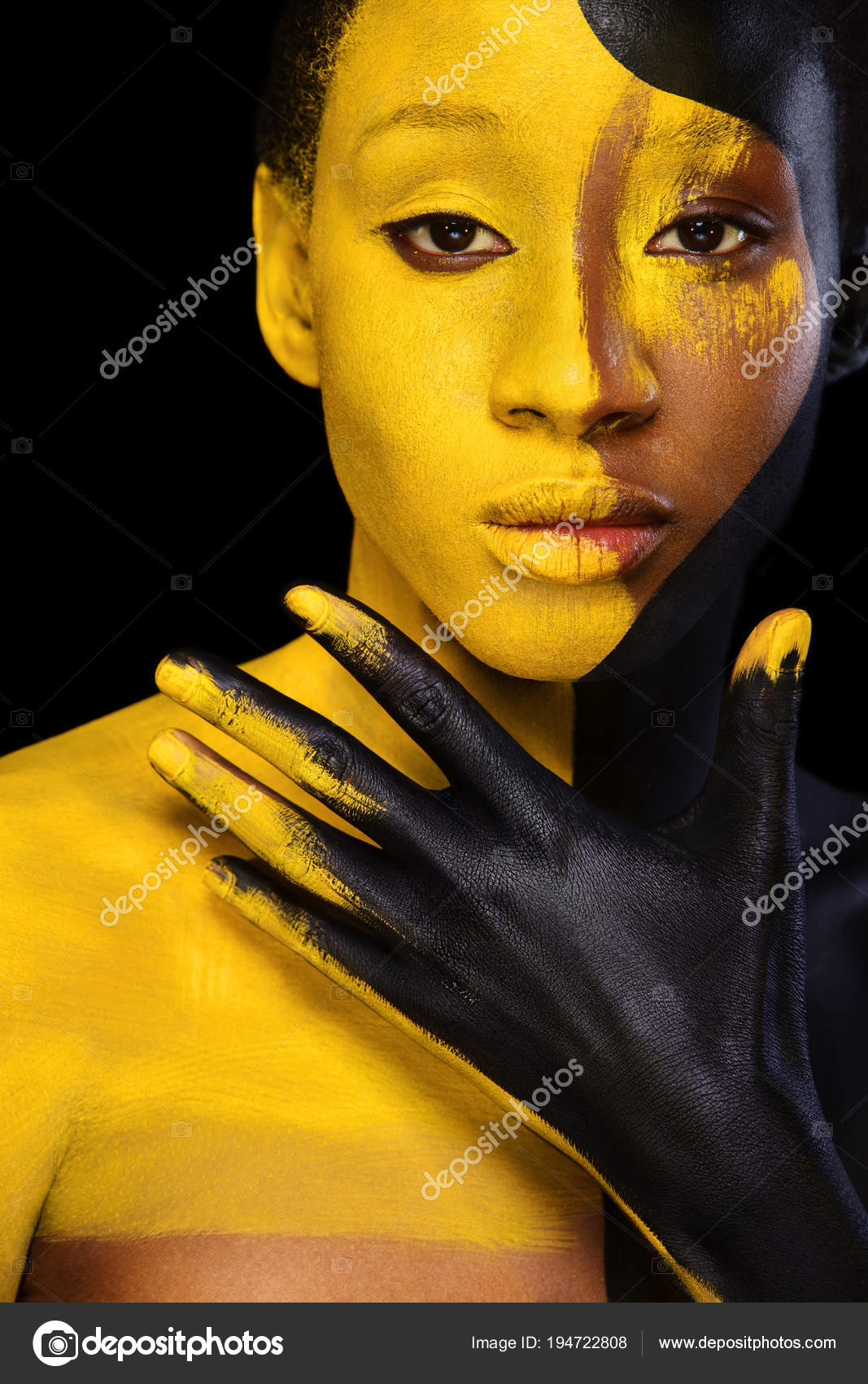 Yellow and black body paint. Woman with face art. Young girl with colorful  bodypaint. An amazing afro american model with makeup. Stock Photo