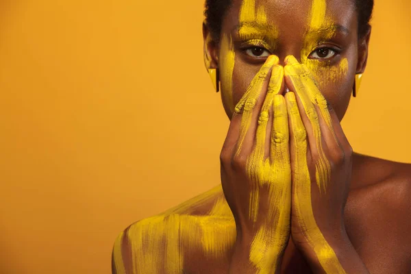 Vrolijke jonge Afrikaanse vrouw met gele voorjaar make-up op haar ogen. Vrouwelijke model tegen geel zomer achtergrond. — Stockfoto