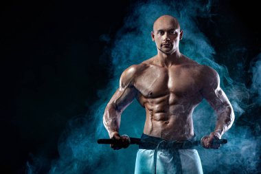 Japon kılıçlı üstsüz samuray. Siyah arka planda dumanlı karate dövüşçüsü. Yakışıklı ve formda sporcu vücut geliştirici fiziği ve atleti. Erkekler spor motivasyonu.