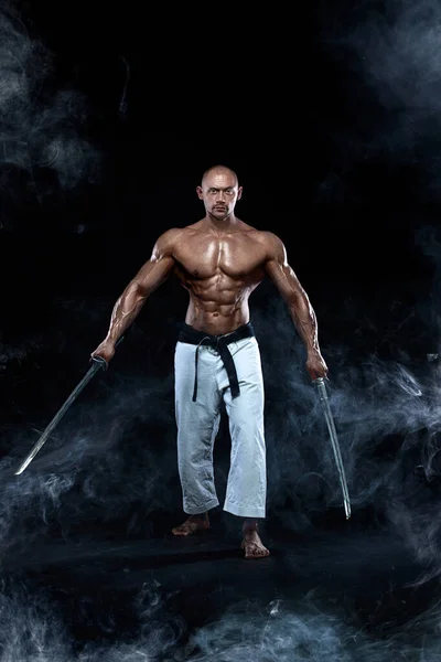 Samurai tanpa baju dengan pedang Jepang. Petarung karate dengan latar belakang hitam dengan asap. Tampan dan pria fit olahraga binaragawan fisik dan atlet. Motivasi olahraga menu . — Stok Foto