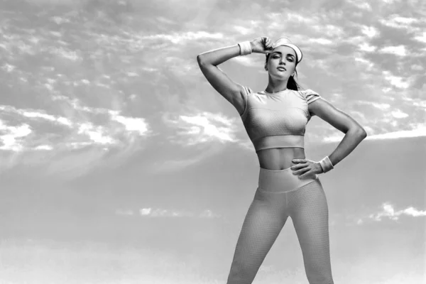 Desportivo e apto jovem atleta relaxado após o treinamento no deserto. Dia nublado na costa. O conceito de um estilo de vida saudável e esporte. Mulher de sportswear branco . — Fotografia de Stock