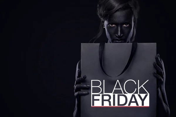 Conceptul de vânzare Black Friday pentru magazin. Femeia de cumpărături cu bodyart și față arta exploatație sac izolat pe fundal întunecat în vacanță . — Fotografie, imagine de stoc