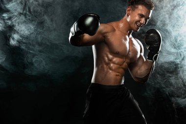 Boksör, siyah arka planda dövüşen ya da poz veren adam. Fitness ve boks konsepti. Bireysel spor eğlencesi.
