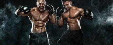 Siyah arka planda eldivenlerle dövüşen iki erkek boksör. Fitness ve boks konsepti. Bireysel spor eğlencesi.