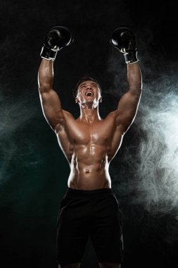 Boksör, boksör galibi ve şampiyon siyah arka planda eldivenlerle kusursuz zaferi kutluyor. Fitness ve boks konsepti. Bireysel spor eğlencesi.