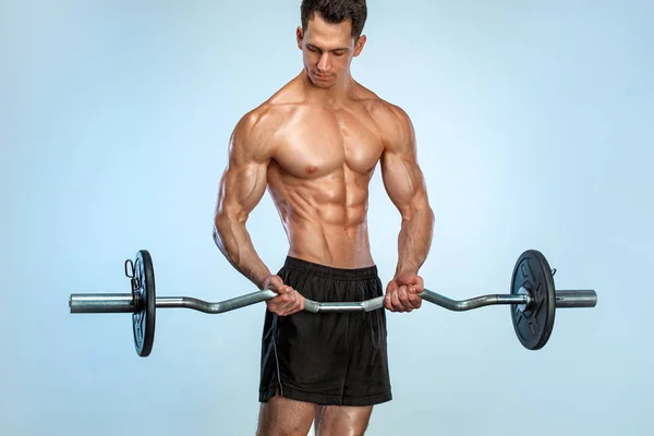 健美运动员。 粗野强壮的肌肉运动员在轻盈的背景上用杠铃抽吸肌肉。 锻炼身体的概念. — 图库照片