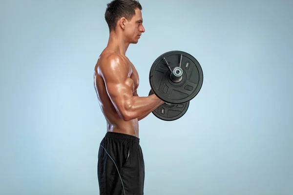 Αθλητής bodybuilder. Σκληρή ισχυρή μυϊκή αθλητικός άνθρωπος άντληση μέχρι τους μυς με barbell στο φως φόντο. Άσκηση έννοια bodybuilding. — Φωτογραφία Αρχείου