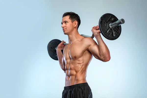 Athlete bodybuilder. Brutal strong muscular athletic man pumping up muscles with barbell on light background. Workout bodybuilding concept. — Stock Photo, Image