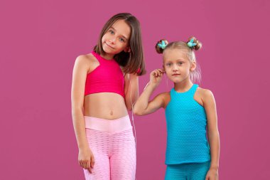 Çocuk yaşam tarzı ve spor anlayışı. İki çocuk kız pembe arka planda müzik dinlerler..
