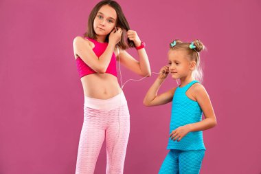 İki çocuk kız pembe arka planda müzik dinler. Çocuk yaşam tarzı konsepti.