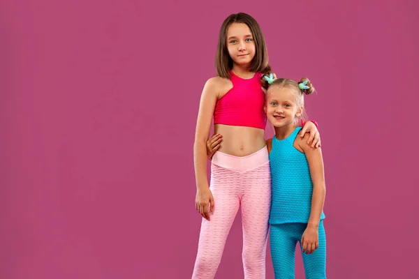 Duas meninas de crianças descansam depois de exercícios de aptidão em um contexto rosa. Crianças conceito de estilo de vida . — Fotografia de Stock