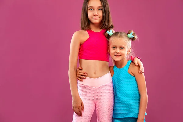 两个女孩在粉色背景下进行健身锻炼后休息。 儿童生活方式概念. — 图库照片