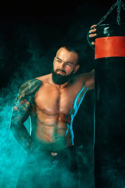 Boxer fighting in gloves with boxing punching bag. Sportsman with tattoos, man Isolated on black background with smoke. Copy Space. — 스톡 사진