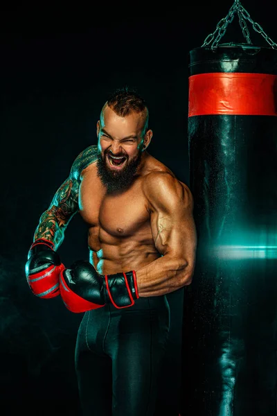 Boxer fighting in gloves with boxing punching bag. Sportsman with tattoos, man Isolated on black background with smoke. Copy Space. — 스톡 사진