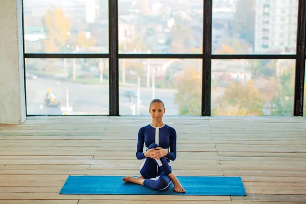 Yoga asana Interior antes de uma grande janela panorâmica. Recreação desportiva. Mulher bonita em pose de ioga. Esportes individuais . — Fotografia de Stock