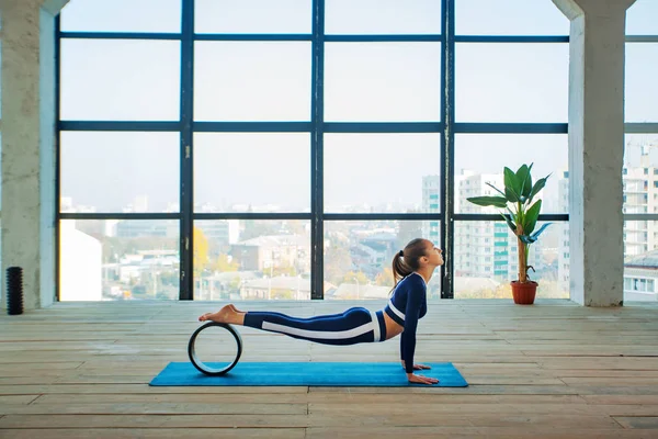 Jóga asana Uvnitř před velkým panoramatickým oknem. Sportovní rekreace. Krásná mladá žena v józe. Individuální sporty. — Stock fotografie