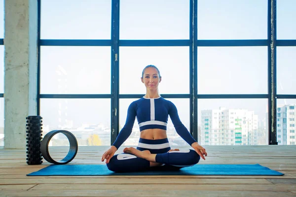 Yoga asana Interior antes de uma grande janela panorâmica. Recreação desportiva. Mulher bonita em pose de ioga. Esportes individuais . — Fotografia de Stock