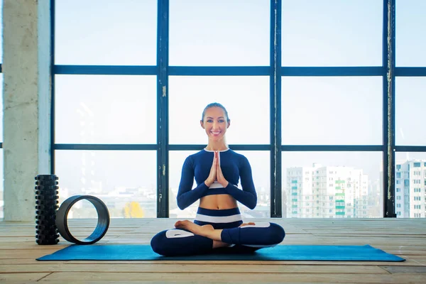 Yoga asana Interior ante una gran ventana panorámica. Recreación deportiva. Hermosa joven en pose de yoga. Deportes individuales . — Foto de Stock