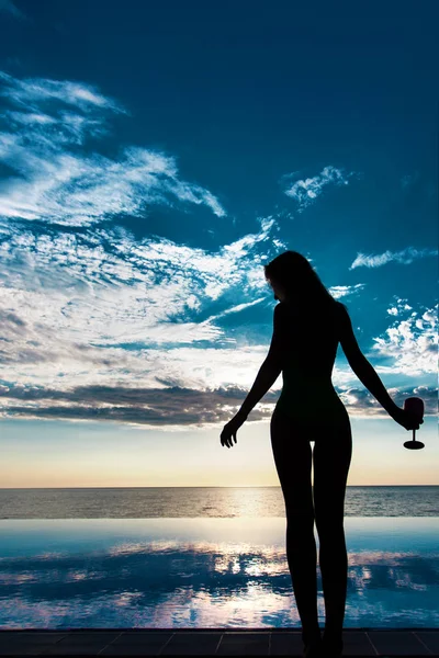 Жінка біля басейну в бікіні з коктейлем. Захід сонця — стокове фото