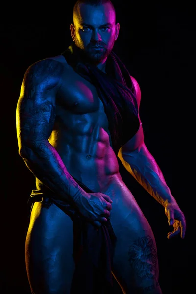 Мускулистый молодой сексуальный красивый мужчина культурист изолирован на черном фоне. Удивленный гей-стрептизер с обнаженным туловищем. Цветные фильтры . — стоковое фото