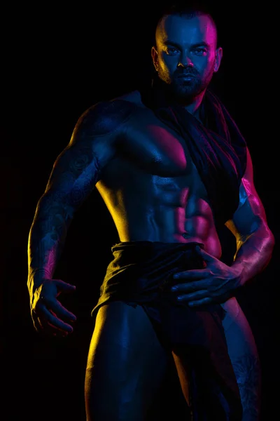 Мускулистый молодой сексуальный красивый мужчина культурист изолирован на черном фоне. Удивленный гей-стрептизер с обнаженным туловищем. Цветные фильтры . — стоковое фото