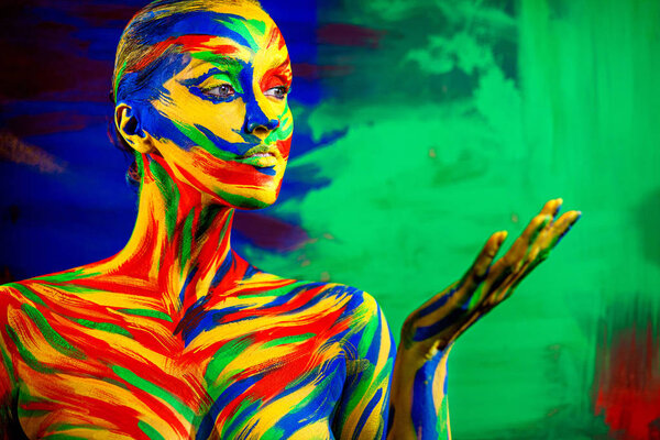 Color art face for inspiration. Abstract portrait of the bright beautiful girl with colorful make-up and bodyart. Woman pointing to looking right.