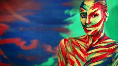 İlham için renk sanatının yüzü. Renkli makyajlı, parlak güzel bir kızın soyut portresi. Neşeli kadın baş parmağını gösteriyor.