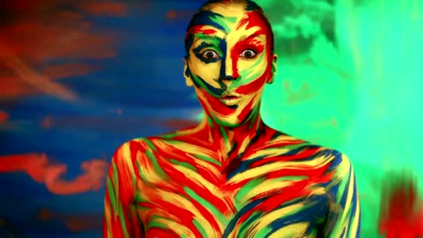 Barva obličeje umění a tělo malovat na ženu pro inspiraci. Abstraktní portrét zářivě krásné dívky s barevným make-upem a bodyartem. Veselá žena projevující wow emoce. — Stock video