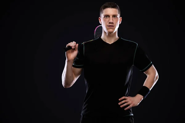 Badminton player in sportswear with racket and shuttlecock on black background. Olympic game. — Stock Photo, Image
