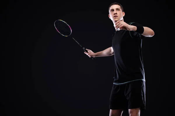 Badminton giocatore in abbigliamento sportivo con racchetta e volano su sfondo nero. Sport individuali. Attività ricreative sportive . — Foto Stock