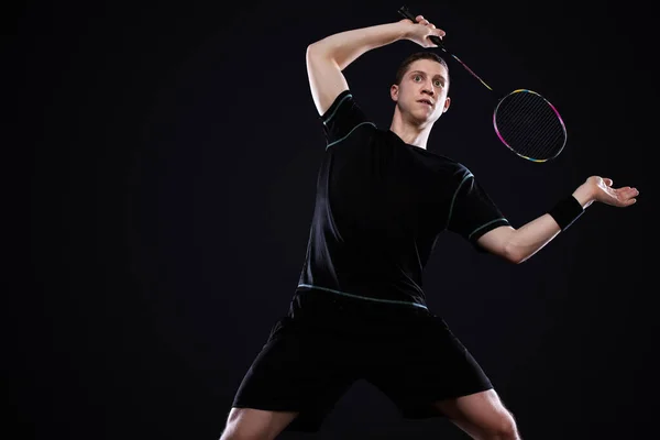 Bádminton jugador en ropa deportiva con raqueta y volante sobre fondo negro . —  Fotos de Stock
