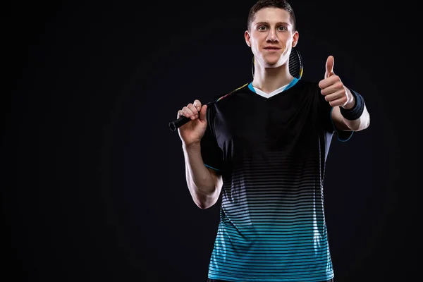 Badminton w odzieży sportowej z rakietą i wahadłowcem na czarnym tle. Emocjonalny portret sportowy z człowiekiem, który pokazuje kciuki wzroku w górę i powodzenia. — Zdjęcie stockowe