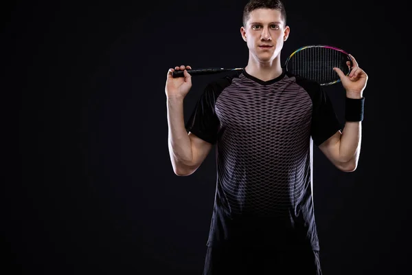 Badminton player in sportswear with racket and shuttlecock on black background. Individual sports. Sports recreation. — Stock Photo, Image