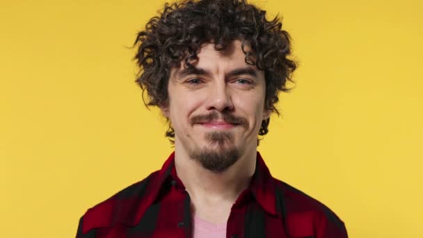 Retrato de primer plano del chico feliz sonriente con el pelo rizado mirando a la cámara aislada sobre fondo amarillo — Vídeo de stock