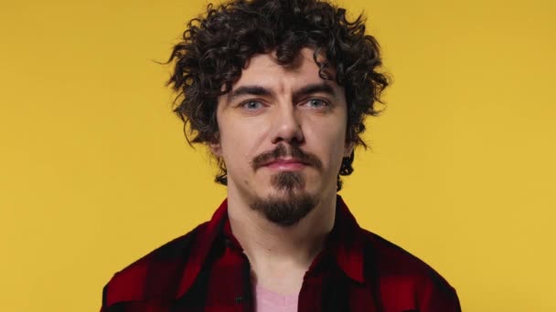 Closeup portrait of surpriced guy with curly hair looking at camera isolated on yellow background. Wow emorion. — ストック動画