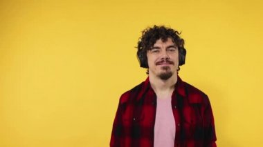 Man shows ok sign with fingers. Closeup portrait of happy smiling guy with curly hair looking at camera isolated on yellow background. Slow motion.