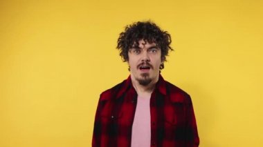 Man celebrates team victory. Closeup portrait of happy smiling guy with curly hair looking at camera isolated on yellow background. Slow motion.