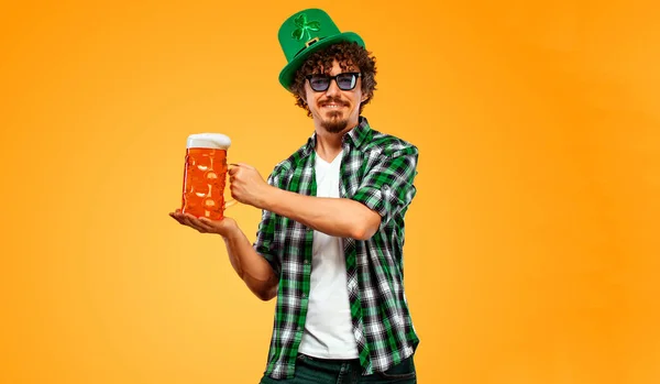 圣帕特里克日。年轻的Oktoberfest男子提供大啤酒瓶与饮料隔离黄色背景。手指头上的手势不错. — 图库照片