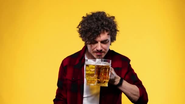 Saint Patrick. Jeune homme Oktoberfest servant une grande tasse de bière avec une boisson isolée sur fond jaune. Le gars montrant les pouces vers le haut signe avec les doigts . — Video