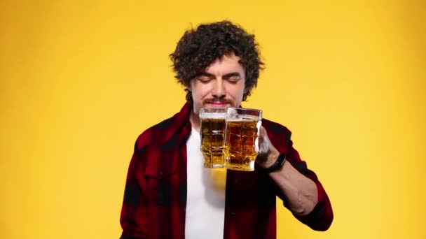 Aziz Patrick Günü. Genç Ekim Festivali adamı, sarı arka planda izole edilmiş büyük bira bardağıyla içki servisi yapıyor. Parmaklarıyla işaret veren adam.. — Stok video