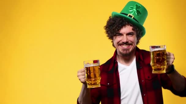 圣帕特里克日。年轻的Oktoberfest男人端着大啤酒瓶，喝着黄色背景的酒. — 图库视频影像