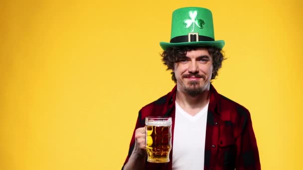 Dia de São Patrício. Jovem Oktoberfest homem servindo caneca de cerveja grande com bebida isolada no fundo amarelo . — Vídeo de Stock