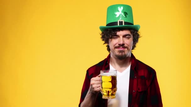 St. Patrick Day. Junger Wiesn-Mann serviert großen Bierkrug mit Getränk auf gelbem Hintergrund. — Stockvideo