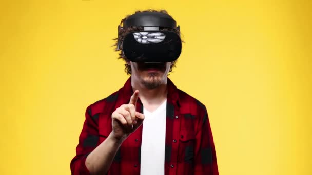 Young man with curly hair using a VR headset and experiencing virtual reality isolated on yellow background — Αρχείο Βίντεο