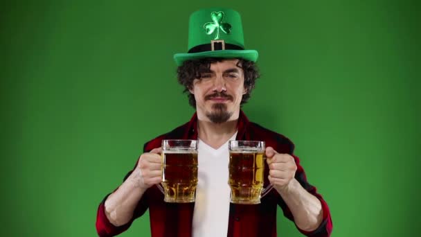 Saint Patrick Day. Young Oktoberfest man serving big beer mug with drink isolated on green background. Slow Motion. Royalty Free Stock Footage