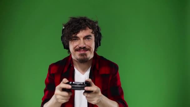 Nerdy gamer with controller on yellow background. Man with curly hair. Chroma key. Slow motion. — Stock Video