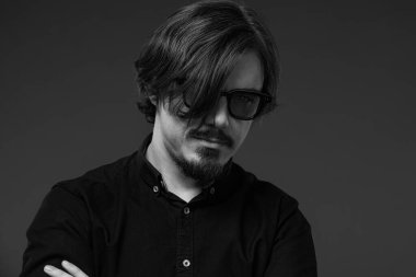 Güneş gözlüklü, uzun saçlı ve sakallı yakışıklı genç müzisyen. Siyah beyaz yakın plan portre.