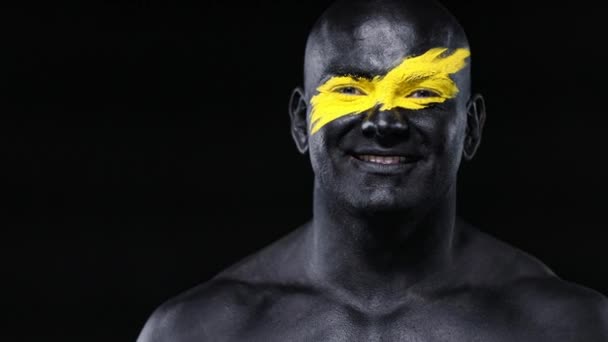 Homme fan de sport et athlète bodybuilder avec la couleur jaune sur le visage et la peinture du corps noir. Portrait coloré du gars avec bodyart. Guy montrant ok signe avec les doigts . — Video