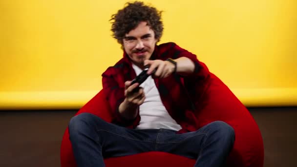 Nerdy gamer with controller on yellow background. Man with curly hair — Stock Video