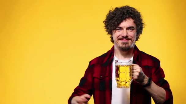 Il giorno di San Patrizio. Giovane uomo Oktoberfest che serve grande tazza di birra con bevanda isolata su sfondo giallo. Guy mostrando ok segno con le dita . — Video Stock